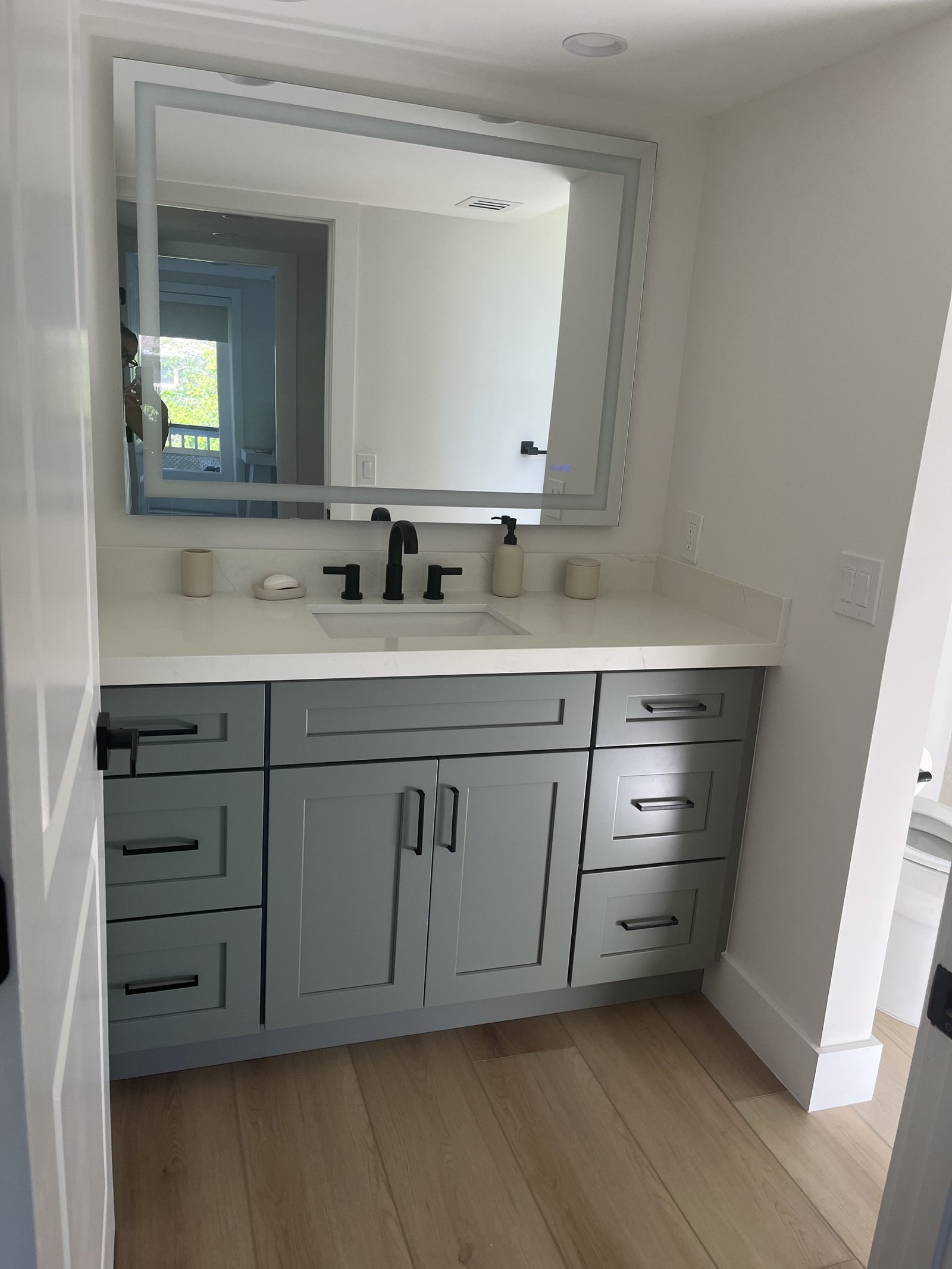 Bathroom vanity with framed mirror and dark hardware